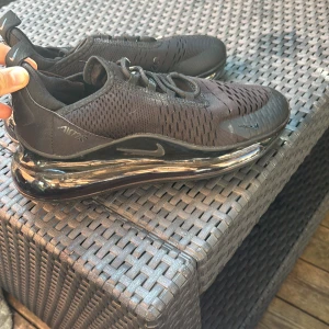 Svarta Nike Air Max sneakers - Säljer ett par helsvarta Nike Air Max sneakers med mesh-ovandel och synlig luftsula. Skorna har snörning och en sportig vibe, perfekt för dig som gillar streetwear. Snygg design med diskreta detaljer och bekväm passform.