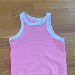Rosa ribbad linnetopp från Zara - Säljer en söt rosa ribbad linnetopp från Zara med vita kanter runt hals och ärmhål. 