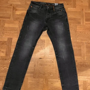 Svarta jeans från riverso, 32/30 - Svarta jeans från riverso med snyggt tvättad look och diskreta slitningar. Klassisk femficksmodell med orangea sömmar vid midjan och knappstängning. Jeansen har en smal passform och är perfekta för dig som gillar en modern stil.