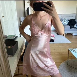Rosa satinnattlinme med spetsdetaljer - Supersöt ljusrosa nattlinne i satin med tunna axelband, spets vid bysten och nederkanten samt en liten rosett framtill. nattlinnet har en feminin v-ringning och ärmlös design som ger en romantisk vibe. aldrig använd!!! 💖