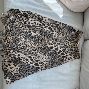 Leopardmönstrad långkjol i satin - Snygg långkjol med leopardmönster i beige och svart. Kjolen har en flowy passform och är tillverkad i ett glansigt satinliknande material som ger en lyxig känsla. Resor i midjan 