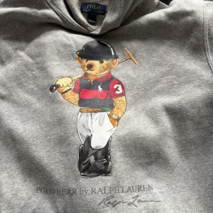  Polo Bear hoodie från Ralph Lauren - Snygg grå hoodie från Ralph Lauren med ikoniska Polo sport. Klassisk streetstyle med en twist av preppy vibe. Storlek 14-16 år (L) 
