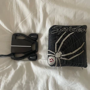 Svart Spider bälte med spindelmotiv - Coolt svart bälte från Spider med broderad spindel och nät i vitt och silver. Bältet har en unik, sportig spänne i svart plast och detaljer i vitt. Perfekt för dig som gillar statement-accessoarer och vill sticka ut.