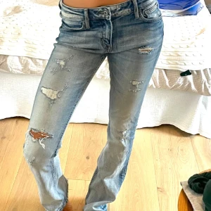 Crocker ljusblå bootcut jeans med slitningar - Ljusblå jeans från Crocker i modellen Pep! Boot med bootcut-ben. Jeansen har snygga slitningar och hål på låren och knäna för en trendig look. Klassisk femficksmodell med dragkedja och knapp. Tillverkade i jeansmaterial med lätt stretch.