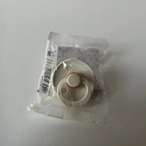 Napp från BIBS  - Säljer en stilren napp från BIBS i färgen ivory. Nappen är rund och tillverkad i latex, med en klassisk design och diskret BIBS-logga framtill. 