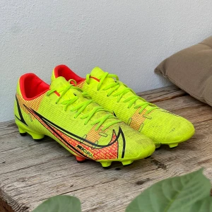 Nike Mercurial fotbollsskor neon - Nike Mercurial fotbollsskor i neon-gul med röda och svarta detaljer. Insidan är röd och yttersulan har svarta och röda dobbar för grymt grepp på planen. Perfekta för dig som vill sticka ut på matchen! Ag/Fg dobbar. Inga slitningar alls bara lite smutsiga! Sänker pris vid snabb affär.