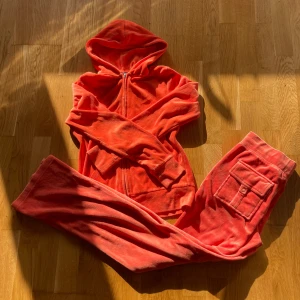 Korallrosa mjukisbyxor med fickor - Säljer ett par korallrosa mjukisbyxor i mjuk frotté med breda ben och stora fickor framtill, varav en med lock och knapp. Byxorna har snörning i midjan för extra chill passform. Perfekta för att hänga hemma eller dra till gymmet i.