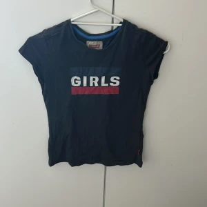 Svart t-shirt från Levi's med tryck - Cool svart t-shirt från Levi's med texten 'GIRLS' tryckt framtill i vitt, blått och rött. Klassisk passform med korta ärmar och rund hals. Perfekt för dig som vill ha en enkel men snygg statement-topp tröjan har inga fläckar men ör lite äldre. Pris kan diskuteras!