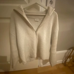 Vit stickad tröja med dragkedja - Mysig vit stickad tröja från Weekday med ribbad struktur och halv dragkedja framtill. 