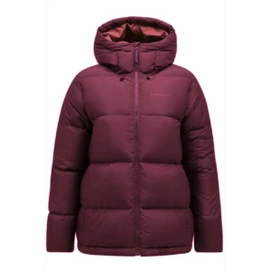 Vinröd dunjacka med huva från peak performance - Säljer en vinröd dunjacka från Peak performance med huva och dragkedja framtill. Jackan är quiltad och har en puffig look som håller dig varm under kalla dagar. Perfekt för dig som vill ha en snygg och funktionell vinterjacka.