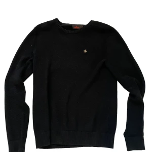 Blå stickad tröja från Morris - Klassisk Blå stickad tröja från Morris med rund halsringning och diskret broderad logga på bröstet. Tröjan har ribbade muddar vid ärmslut och nederkant, perfekt för en stilren och enkel look.