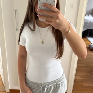 Vit tight kortärmad body - Säljer en vit, tight och figurnära body med korta ärmar. Materialet känns mjukt och stretchigt.