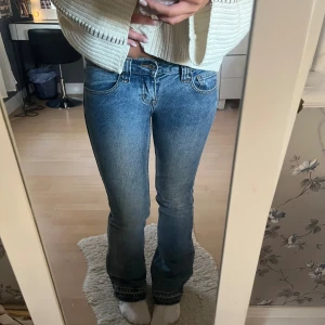 Blå bootcut jeans med låg midja - Snygga blå jeans med bootcut-modell och låg midja. Jeansen har klassisk femficksdesign, bälteshällor och dragkedja med knapp. Materialet är jeans i bomull och passformen är normal med lätt utsvängda ben. Midjemåttet är 38 rakt över och innerbenslängden är 80🩷