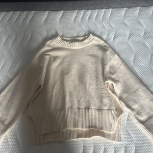 Beige stickad tröja från Pull&Bear - Mysig beige stickad tröja från Pull&Bear. Tröjan har bred ribbad mudd vid ärmslut och nederkant samt rund halsringning. Perfekt för lager-på-lager och chill vibes. Helt ny aldrig använt den