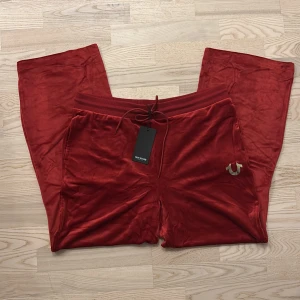 Röda velourbyxor från True Religion🤎 - Riktigt snygga vin/roströda velourbyxor från True Religion i rak modell. Byxorna har resår och snörning i midjan samt den ikoniska loggan i silver på fickan. Supermjuka!! 🤎