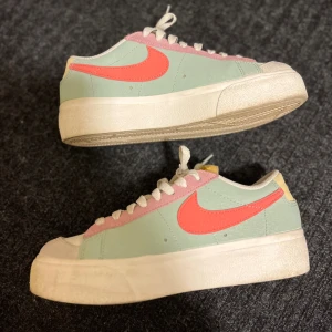 Nike Blazer Low pastell sneakers - Nike Blazer Low sneakers i fräscha pastellfärger med mintgrön bas, rosa detaljer och en stark korallröd swoosh. Skorna har vit platt sula, snörning och gul tunga. Perfekt för dig som gillar färg och vill sticka ut med din stil.