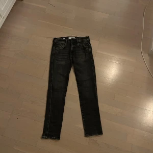 Replay svarta jeans, waist 29 L 30 - Snygga svarta Replay anbass jeans med slitningar och slim fit. Tillverkade i ekologisk bomull, klassisk femficksmodell och dragkedjegylf. Perfekta för dig som gillar en smal siluett och laid back-inspirerad look.