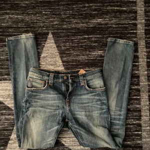 Blå jeans från Nudie Jeans - Säljer nu ett par riktigt snygga jeans från nudie, de är i storlek W29 L32 och i modell Grim Tim de har endast en defekt (bild 1 en liten slitning längst ned) men annars i bra skicka hör dig av vid intresse!💫