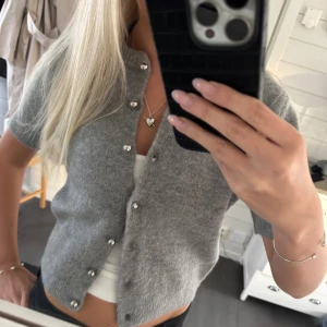 Grå kortärmad kofta🩶 - Superfin grå kofta med korta ärmar och pärlknappar framtill. Koftan är stickad och har en mjuk, fluffig känsla. Perfekt att slänga över ett linne för en chill och snygg look.