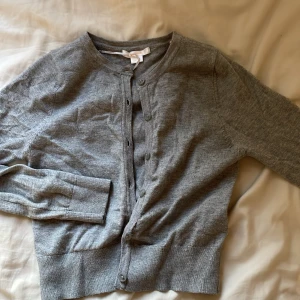 Grå kofta från Gina Tricot Young  - Grå kofta från Gina Tricot med rund halsringning och knappar hela vägen framtill. Säljer pga av att den är för liten 💞