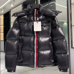 Svart pufferjacka med rödvit rand - Snygg svart pufferjacka med glansig finish och en tydlig rödvit rand längs dragkedjan. Jackan har hög krage, stora vadderade partier och praktiska fickor. Perfekt för kalla dagar när du vill hålla stilen och värmen.