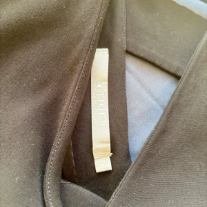 Svart kortklänning från Tiger of Sweden - Stilren svart kortklänning från Tiger of Sweden, modell NILEA. Klänningen har v-ringning, korta ärmar och en snygg detalj med liten öppning baktill. Tillverkad i ett slätt tyg som ger en klassisk och clean look. rak modell, kan modifieras med ett skärp ju om man känner för det