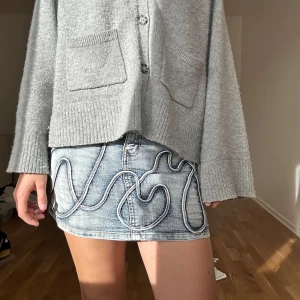 Blå jeanskjol med detaljer från cFLUK - Säljer en blå jeanskjol från cFLUK med coola sydda vågiga detaljer framtill och bak. 