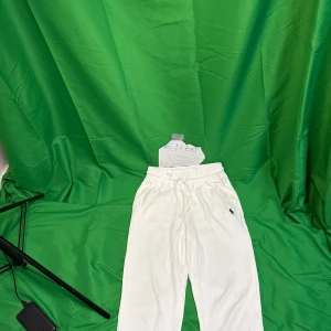 Vita mjukisbyxor från Ralph Lauren - Snygga vita mjukisbyxor från Ralph Lauren med elastisk midja och snörning. Byxorna har sidofickor, en bakficka och den klassiska blå Polo-loggan broderad på ena benet. Perfekta för en chill och avslappnad stil.Liknande modell som originalet!