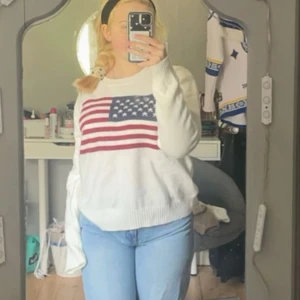 Vit stickad tröja med USA-flagga - Vit stickad tröja med amerikansk flagga på bröstet. Tröjan har rund halsringning och långa ärmar. Perfekt för dig som gillar en casual och cool stil med en touch av USA-vibe🩷