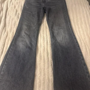 Grå bootcut jeans  - Säljer ett par blå jeans med bootcut-modell och breda ben. Jeansen har klassisk tvättad look och är tillverkade i jeansmaterial. Perfekta för dig som gillar en retrostil med extra vidd nertill.