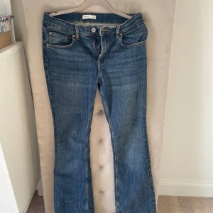 Blå bootcut jeans från Gina Tricot - Snygga blå jeans från Gina Tricot med klassisk bootcut-modell. Jeansen har fem fickor, normal midja och är tillverkade i ett mjukt denimtyg av bomull. Perfekt för dig som gillar en tidlös och avslappnad stil. Lite slitna längst ner 