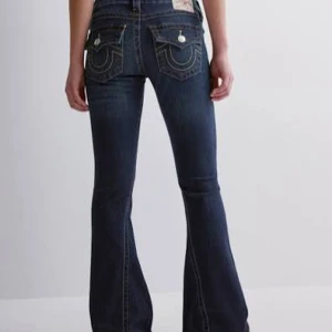 True Religion Joey Low Rise Flare Jeans - Säljer ett par mörkblå True Religion Joey lowwaist flare.De är strl 26 men sitter som en 27 tror jag eftersom de har töjts ut!Jätte bra skick men längs ner har de blivit lite slitna eftersom de va för långa!