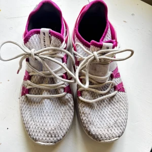 Vita och rosa sneakers med mesh - Snygga sneakers från Fabletics i vitt och rosa med sportig design. Ovandelen är i ventilerande mesh och detaljer i rosa syntet. Skorna har snörning och en chunky sula som ger en cool look. Perfekta för dig som gillar en aktiv stil. Gör man rent dom så är skorna nästan som nya. Men det orka inte jag 