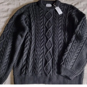 Grå stickad/kabelstickad tidlös tröja - Vailent - storlek M - Grå stickad tröja i en klassisk modell. Storlek M. Oanvänd och ordinarie pris var 699. 