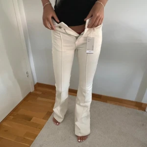 Beige bootcut byxor med pressveck Mango - Snygga vita bootcut byxor med markerade pressveck framtill. Byxorna har hög midja och stängs med knapp och dragkedja. Perfekta för en clean och fräsch look 💓💓