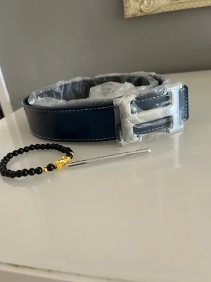 Mörkblått H bälte  - Säljer mitt herrmes bälte 115cm helt nytt. Armband ingår. Hör av er vid frågor och funderingar 