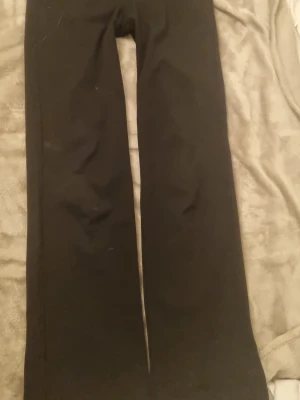 Svarta straight byxor från Vero Moda - Svarta byxor från Vero Moda i modellen VMZamira MR Slim Straight Pant. De har rak passform och midwaist, vilket ger en clean och stilren look. Materialet är mjukt och bekvämt, perfekt för dig som gillar enkel och snygg stil. Passar dig som vill ha ett par klassiska svarta byxor.