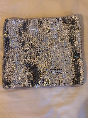 Silvrig paljett-tubtopp från Alivila.y - Säljer en glittrig tubtopp från Alivila.y, helt täckt med silvriga paljetter. Toppen är bandeau-modell och har en mjuk insida för extra komfort. Perfekt till fest och går även och använda som kjol!!