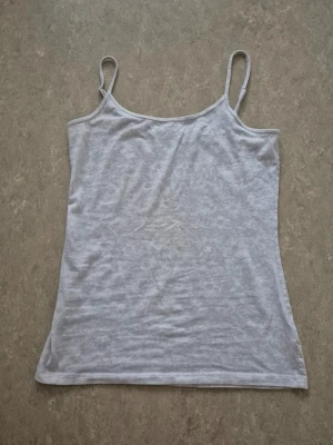 Linnetopp - Säljer en enkel och stilren vit linnetopp från Nollie i storlek S/M. Toppen har smala axelband och ärmlös design, perfekt för varma dagar. Materialet är mjukt och lätt bomull som känns skönt mot huden. Passformen är normal och toppen har en klassisk rak form.