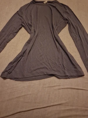 Mörkgrå långärmad topp med nitar - Snygg mörkgrå långärmad topp i mjukt material. Ärmarna är dekorerade med små silverfärgade nitar som ger en cool touch. Perfekt till jeans eller kjol för en trendig look. Den är tunn så passar väldigt bra under sommaren. Osäker på märke, jag säljer en likadan från showgirls så jag antar att denna också är från showgirls. Passar dig med S eller M storlek om du vill ha tight passform. Passar även XS men inte lika tight. Priset som står gäller, kan möjligtvis diskuteras 🫶