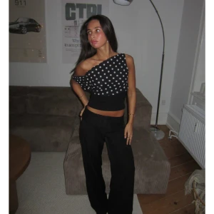 Svart oneshoulder topp - Säljer denna supersnygga topp (KIMMIE POLKA DOTTED TOP) från Designbysi. Svart topp med vita prickar och oneshoulder-design. Croppad modell som sitter tight över midjan . Storlek M, men lite mindre i storleken.