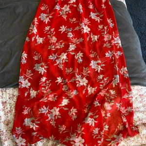 Röd blommig långkjol i polyester - Säljer en röd långkjol med blommigt mönster i ljusa toner. Kjolen är gjord i 100% polyester och har en mjuk, flowy känsla. Perfekt för dig som gillar färgstarka och romantiska plagg. Passar storlek 38❤️