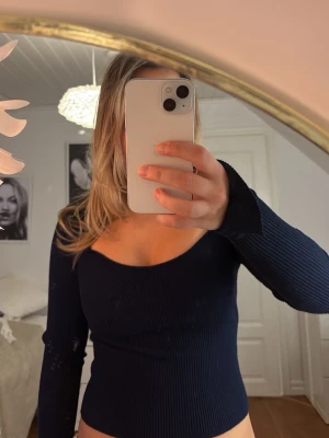 Mörkblå ribbad topp från Gina Tricot - Säljer en mörkblå långärmad topp från Gina Tricot i storlek S. Toppen är ribbad, har en snygg v-ringad urringning och långa ärmar med tumhål. Perfekt att styla med jeans eller kjol för en trendig look.