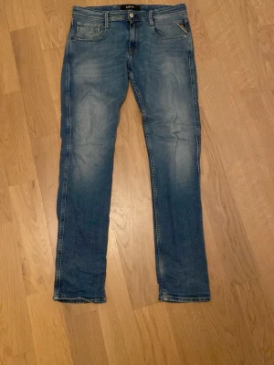 Replay anbass jeans blå, storlek 30/32 - Säljer ett par snygga Replay anbass jeans i klassisk blå tvätt med raka ben och fem fickor. Använda varsamt men har lite småslitningar längst ner på benen. Köpare står för frakt.