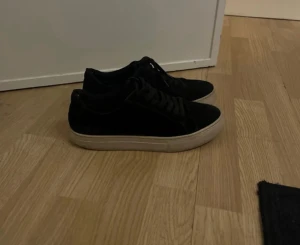 vagabond skor - Stilrena svarta sneakers med tjock vit sula och snörning. Skorna har en klassisk låg profil och rund tå, vilket gör dem enkla att matcha till olika outfits. Materialet ser ut att vara syntet eller mocka för en mjuk känsla.