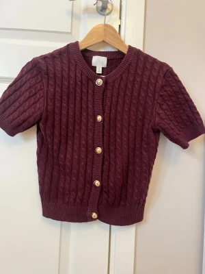 Vinröd kofta - Vinröd kabelstickad kofta från H&M med korta ärmar 