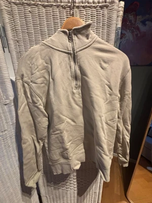 Beige halfzip sweatshirt från Zara - Säljer en beige sweatshirt från Zara med halv dragkedja framtill och hög krage. Tröjan har avslappnad passform, långa ärmar och ribbade muddar. Perfekt för en chill och stilren look.
