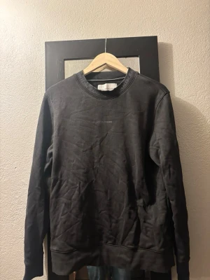 Svart sweatshirt från Calvin Klein Jeans - Snygg svart sweatshirt från Calvin Klein Jeans med diskret logga på bröstet och textdetaljer runt halsringningen. Tröjan har rund hals, långa ärmar och ribbade muddar. Perfekt för en avslappnad och stilren look.