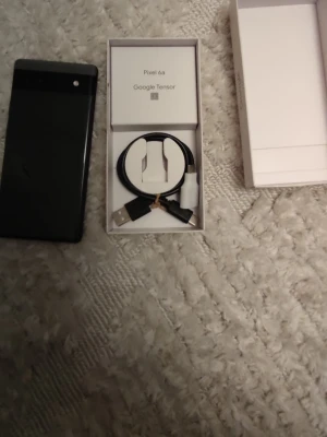 Google Pixel 6a svart med tillbehör - Google Pixel 6a i svart med stilren design och bakstycke i glas. Levereras med originalkartong, USB-C laddningskabel och adapter. Telefonen har en rektangulär form och en tydlig kameramodul upptill på baksidan. Perfekt för dig som gillar Android och vill ha en smidig mobil. Telefonen är i mycket bra skick det finns repor på skyddsskärm annars är den helt bra. Skal till mobilen följer med också även simkort också men är ej säker om de funkar.
