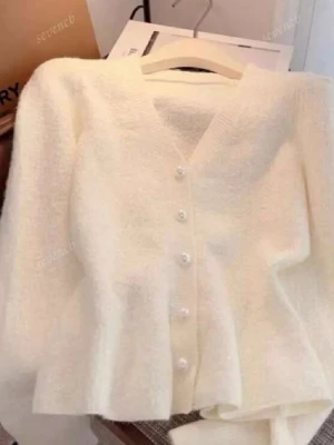 Vit fluffig kofta med pärlknappar - Mysig vit kofta med fluffig textur och v-ringning. Koftan har långa ärmar och stängs med dekorativa pärlknappar framtill. Perfekt för lager-på-lager och en stilren look.